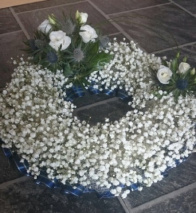 Gypsophila Open Wreath - This beautiful tribute was created using gypsophila instead of the more traditional chrysanthemums and has a lovely Scottish feel with the tartan ribbon and thistle corsages! Ribbon and corsages can vary depending on your preference. Standard 12", Deluxe is 14" and luxury 16"